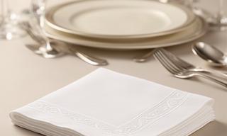 White embossed dinner napkins arranged beside a formal place setting